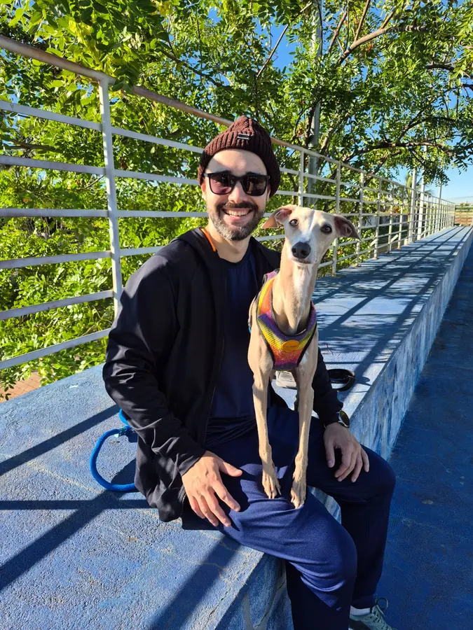 Lucas sentado com o cachorro Lion no passeio diário